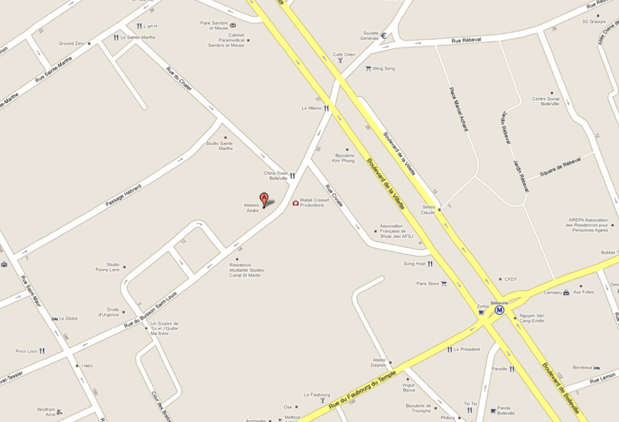 L'image montre une carte de rue avec plusieurs routes et intersections. On peut observer des voies de circulation, des noms de rues, et un point marqué qui semble indiquer un emplacement particulier. La carte est dessinée de manière simplifiée, avec une couleur claire pour le fond et des lignes pour les routes. Des repères et des informations sur des points d'intérêt peuvent également être présents, mais ils ne sont pas spécifiques dans cette image.