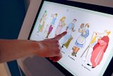 L'image montre une interface d'écran tactile avec des illustrations de personnes en costumes historiques ou traditionnels. Une main pointe vers l'un des personnages, qui semble discuter des métiers ou des rôles spécifiques, tels que "le polier" et "le peintre". Les dessins sont colorés et stylisés, et le fond de l'écran est sobre, mettant en valeur les illustrations.