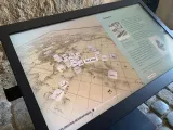 L'image montre un écran interactif qui présente une carte de l'Océanie. Sur la carte, plusieurs marqueurs sont disposés, probablement représentant des lieux d'intérêt ou des points historiques. À droite de l'écran, il y a un texte explicatif, tandis que le titre indique "Exploration Géographique" et "Exploration Maritime". Le fond de l'image semble être une pierre, suggérant que l'écran est installé dans un lieu historique ou un musée.