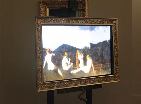 L'image semble représenter une œuvre d'art en format numérique, encadrée dans un cadre orné. On peut y voir des figures humaines, probablement nues, disposées dans un paysage avec des montagnes en arrière-plan. Les personnages sont assis ou posant de manière contemplative, suggérant une atmosphère paisible. La qualité de l'image peut donner l'impression d'un tableau classique, mais avec une touche moderne grâce à l'écran numérique.